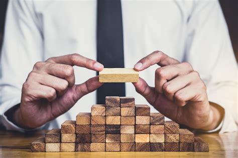 Premium Photo Midsection Of Businessman Stacking Wooden Blocks On Table