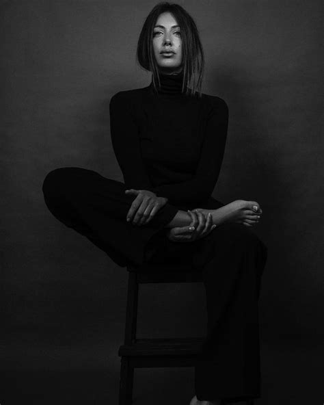 A Woman Sitting On Top Of A Wooden Chair In Black And White Photo With