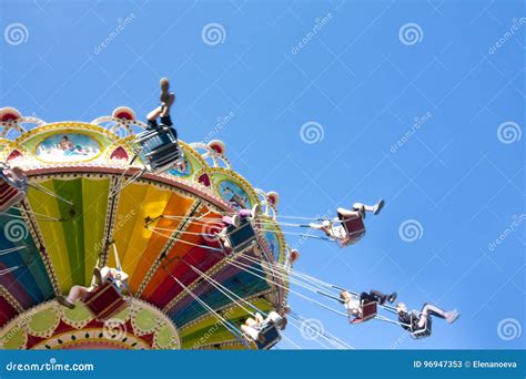 Colorful Chain Swing Carousel In Motion At Amusement Park On Blue Sky