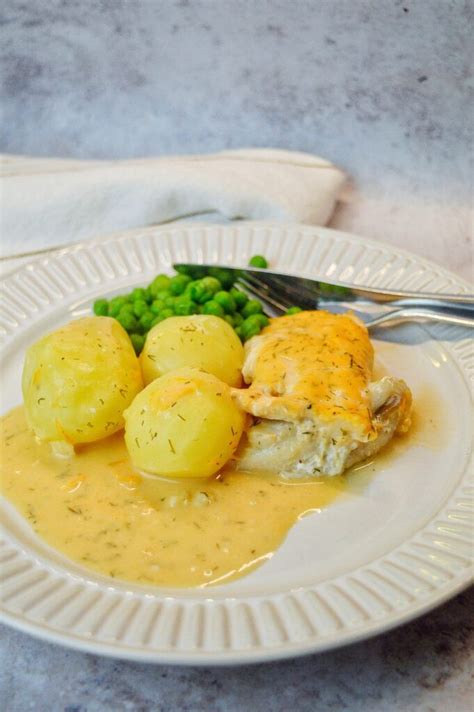 A White Plate Topped With Chicken And Potatoes Covered In Gravy Next To