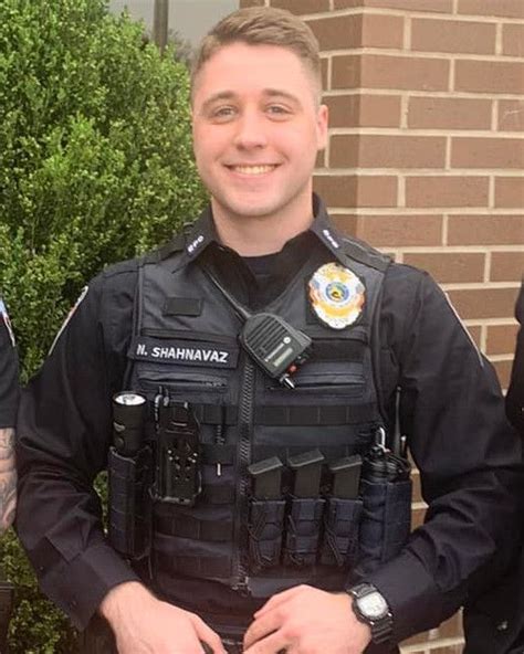 Two Police Officers Standing Next To Each Other In Front Of A Brick