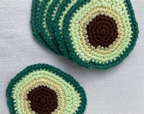 Four Crocheted Coasters With Green And Brown Circles On White Cloth