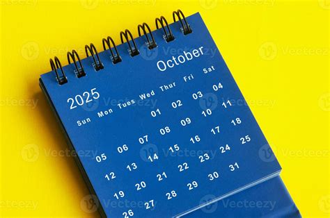 October 2025 blue desk calendar on yellow cover background. 36483403