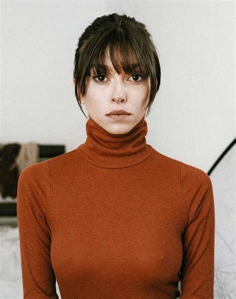 A Woman In A Brown Turtle Neck Sweater Posing For The Camera With Her