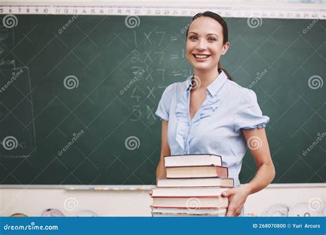 Caring Teacher A Pretty Teacher Holding A Stack Of Books In Her