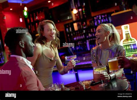 Four Happy Diverse Male And Female Friends Drinking And Talking At The