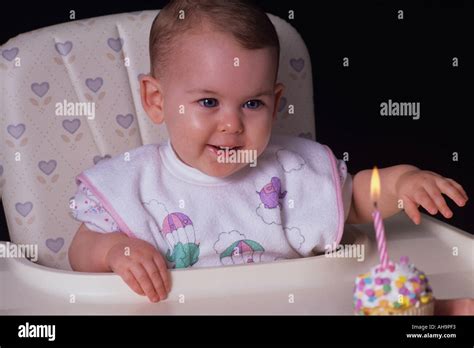 Babys First Birthday Sitting In Highchair With Surprised Happy Look On