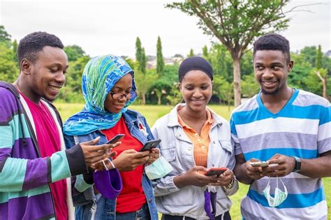 Grupo de jovens amigos africanos máscaras usando seus telefones em