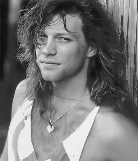 A Man With Long Hair Standing Next To A Wall