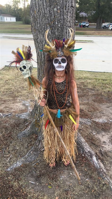 a woman in costume standing next to a tree with two skulls on her head ...