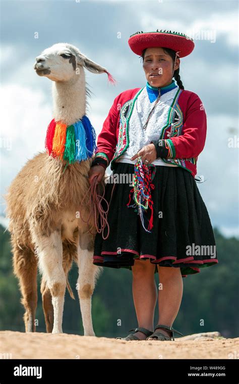 A Lady Dressed In Traditional Peruvian Clothes With Her Llama At The