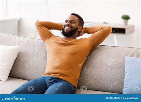 Happy African American Man Relaxing Sitting On Sofa At Home Stock Image