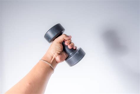 Premium Photo Cropped Hand Of Woman Lifting Dumbbell Against White