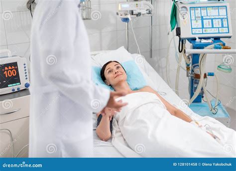 Beautiful Young Lady Looking At Doctor While Lying In Hospital Bed