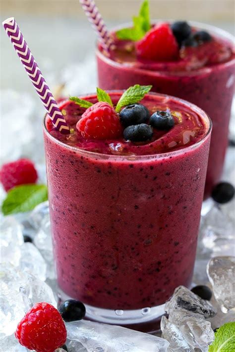 A glass of frozen fruit smoothie with a straw, topped with raspberries ...