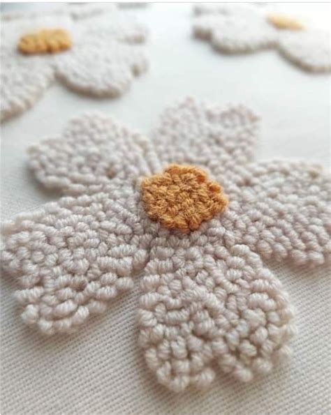 A Crocheted Flower Is Shown On A White Surface With Yellow Center And