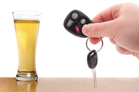 Drunk Driving Concept Image With A Hand Holding Some Car Keys And A Glass Of Beer Isolated Over