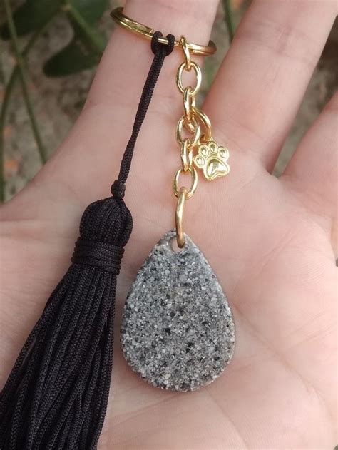 A Hand Holding A Stone With A Tassel On It S End And A Key Chain