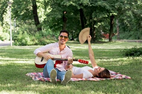 Hombre Sonriente Tocando La Guitarra En El Parque Foto Gratis