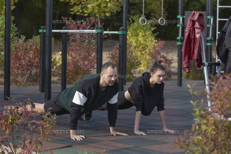 Athletic Young Couple Doing Plank Exercises At Park Playground