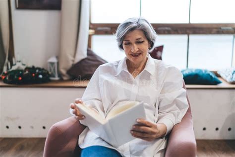 Idosa Positiva Que Gosta De Ler Livros Na Sala De Estar Imagem De Stock