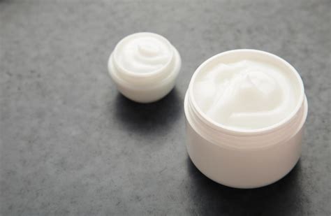 Creme hidratante facial em uma jarra em fundo escuro cosméticos