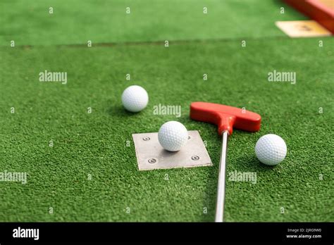 Assorted Miniature Golf Putters And Balls Askew On Synthetic Grass