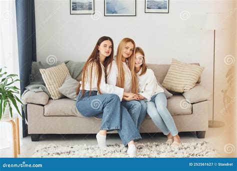 Sitting On The Sofa Young Mother With Her Two Daughters At Home At