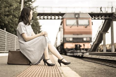 Una Hermosa Chica En La Plataforma Está Sentada En Una Maleta En El Contexto De Un Tren Que Se