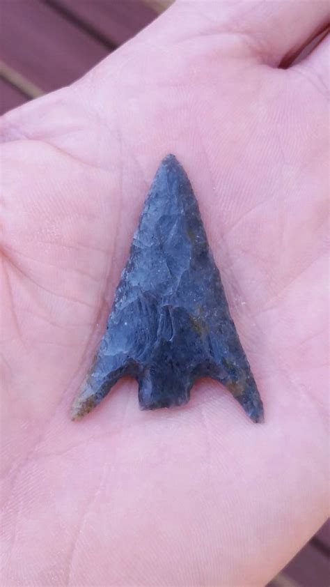 A Hand Holding A Piece Of Blue Rock With A Small Triangle Shaped Object