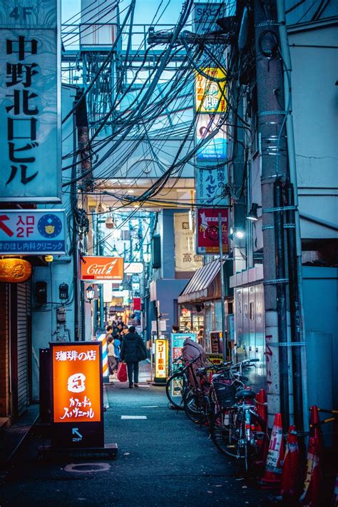 an alley way with lots of electrical wires and people walking down the ...