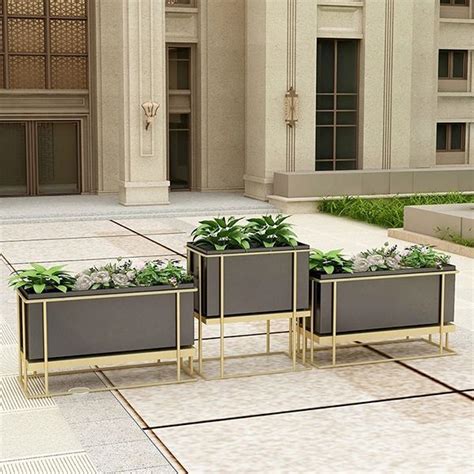 Three Planters With Plants In Them On The Ground