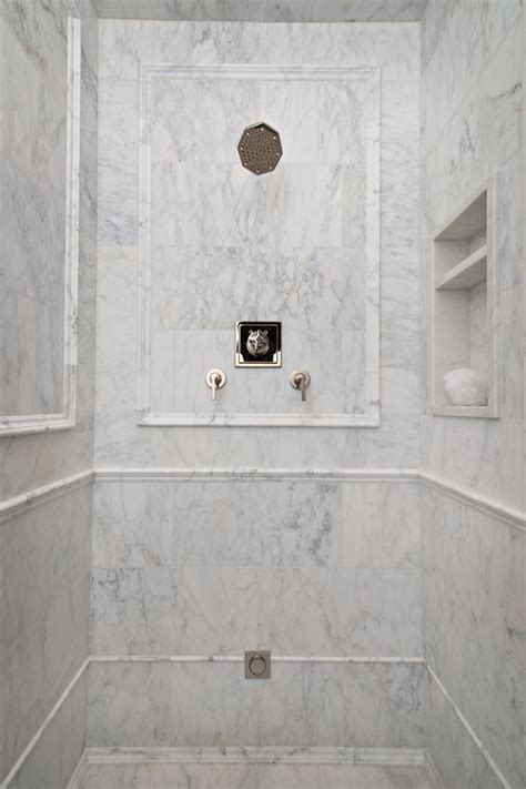 A Bathroom With White Marble Walls And Flooring Including A Shower