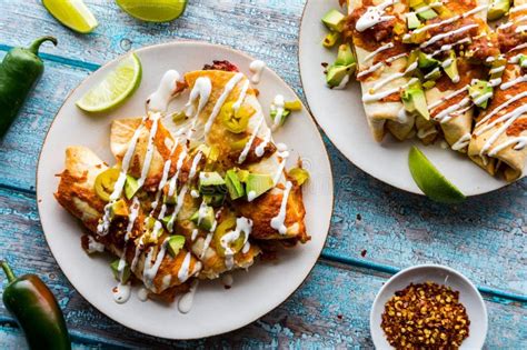 Top Down View Of Taquitos Topped With Salsa Avocado And Sour Cream