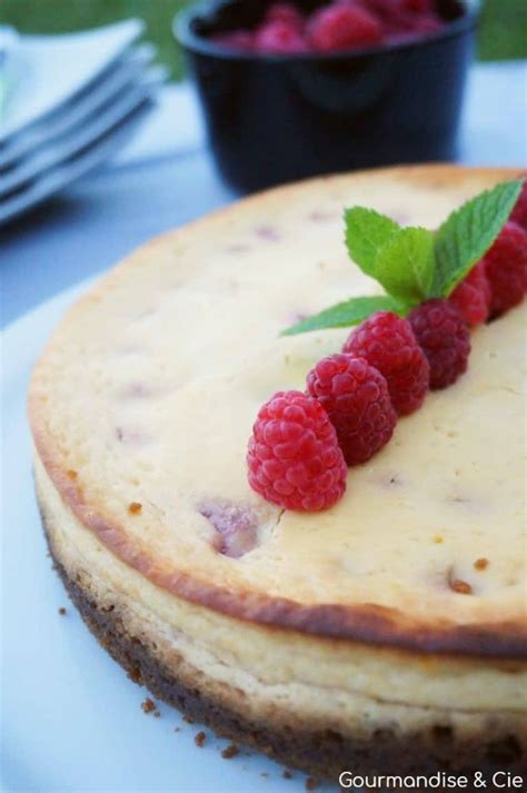 A Cheesecake Topped With Raspberries On Top Of A White Plate