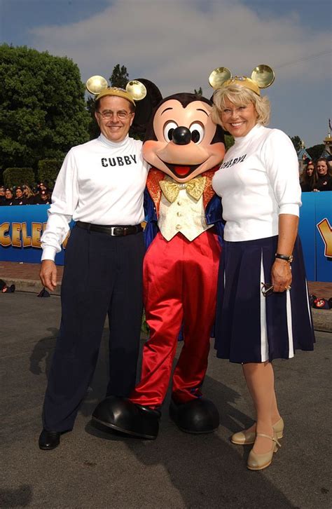 Two People Standing Next To Mickey Mouse At An Event