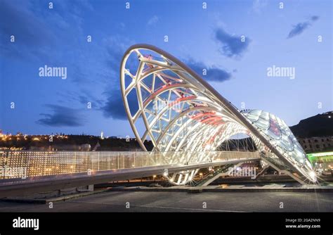 The Bow Shaped Bridge Of Peace Pedestrian Bridge Illuminated At Dusk Spanning The Mtkvari Kura