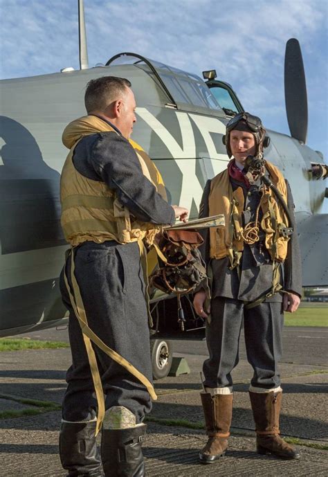 Two Men Standing Next To Each Other In Front Of An Airplane