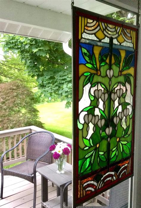 A Stained Glass Window Sitting On Top Of A Wooden Porch Next To A Chair