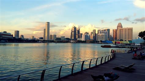 People On Park Viewing City With High Rise Buildings And Body Of Water