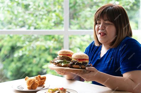 Premium Photo Hungry Overweight Woman Holding Hamburger On A Wooden