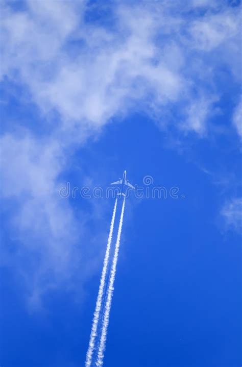 Plane Flying High In The Blue Sky And Leaves A Long White Trail Stock