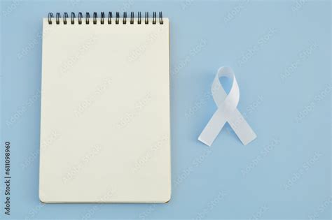 White Ribbon As A Symbol Of Peace And White Notebook On Blue Background