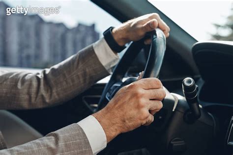 Close up of man holding hands on steering wheel while driving a car 이미지