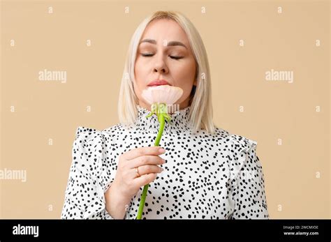 Mature Woman With Beautiful Flower On Beige Background International