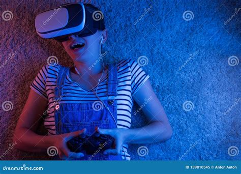 Una Muchacha Con Un Gamepad En Vidrios Del Vr Jugando Con La Luz Azul