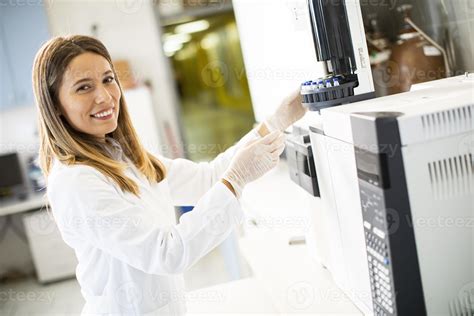 Female Scientist In A White Lab Coat Putting Vial With A Sample For An