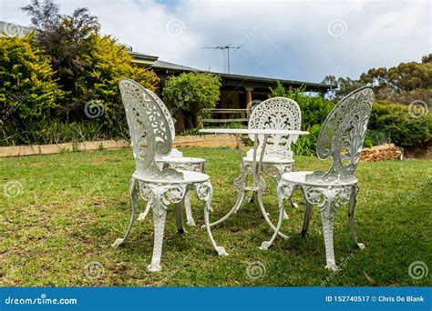 Tabela E Cadeiras Brancas Do Ferro Fundido No Jardim Imagem De Stock