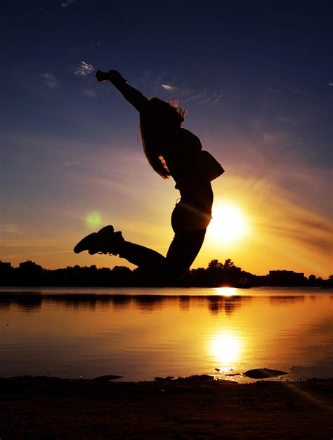 Woman Jumping Near Body Of Water Free Stock Photo