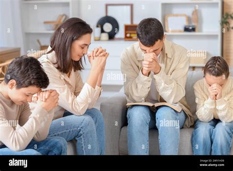 Family with Holy Bible praying on sofa at home Stock Photo - Alamy